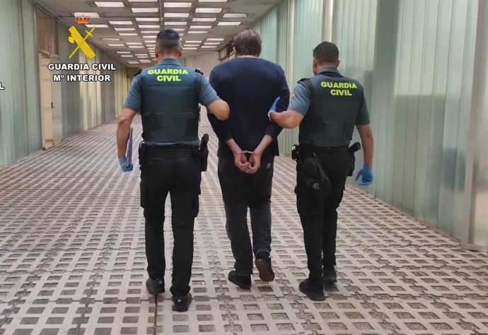 El detenido, conducido por agentes en las instalaciones del aeropuerto.