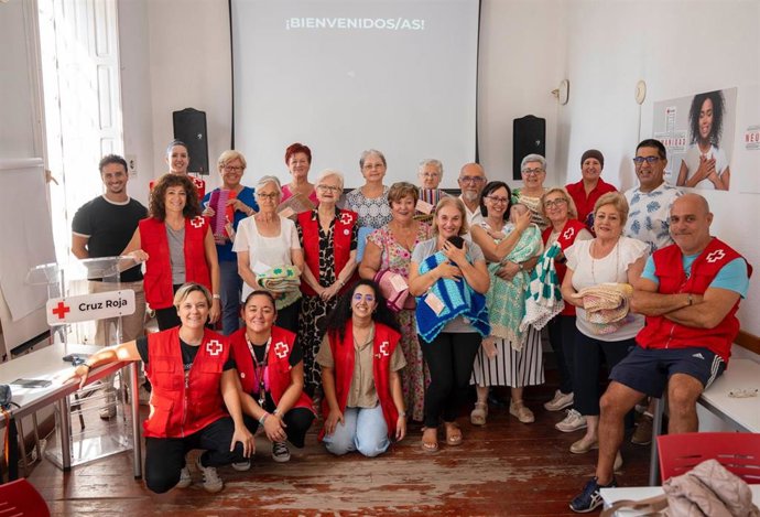 Participantes del proyecto 'Enrédate' de Cruz Roja en Almería, junto a voluntariado y familias acogedoras, durante el acto de entrega de las mantas de cuna.
