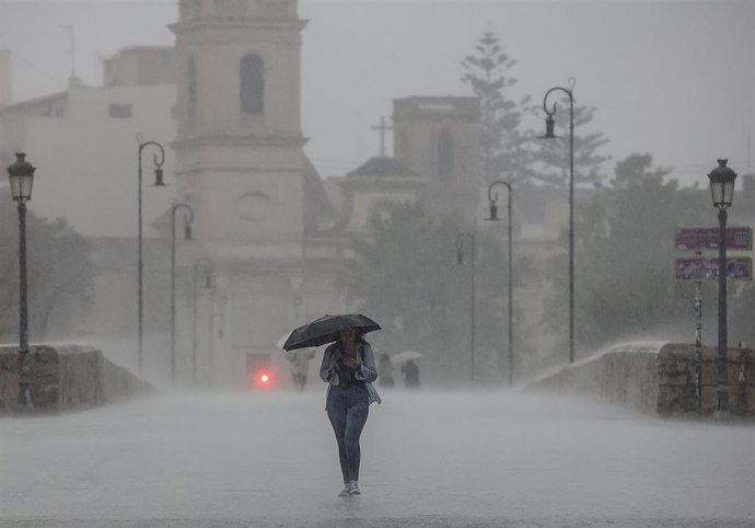 Archivo - Una persona camina con un paraguas bajo la lluvia, a 15 de septiembre de 2023, en València