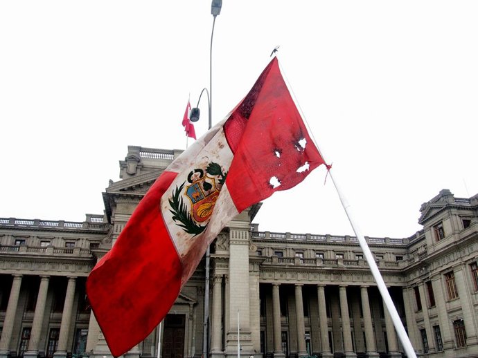 Archivo - Arquivo - 28 de julho de 2025, Lima, Lima, Peru: A bandeira peruana manchada, perfurada e esfarrapada é agitada quando dezenas de parentes de vítimas mortas em protestos durante o governo de Dina Boluarte se reúnem em frente ao Palácio da Justiç