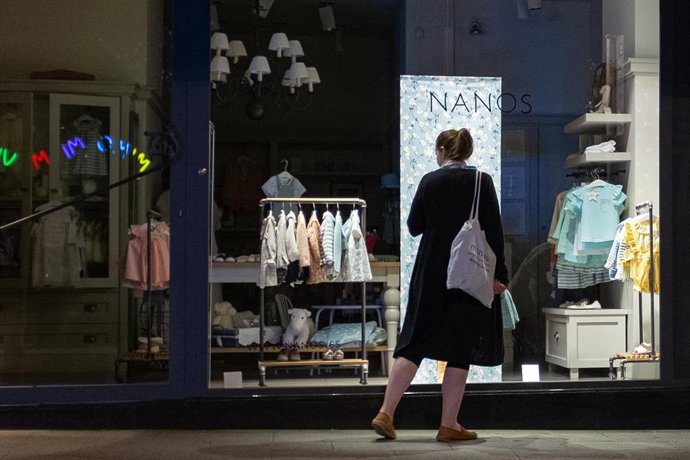 Archivo - Una mujer observa el escaparate de una tienda
