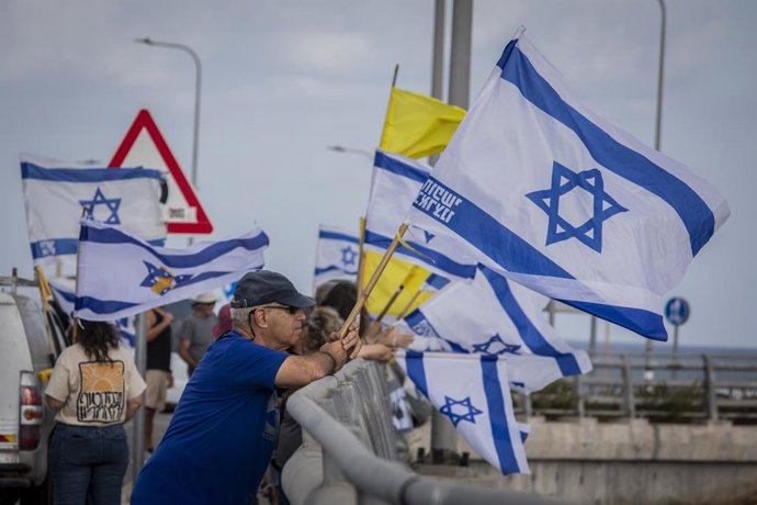 Archivo - Arquivo - 26 de agosto de 2025, Beit Yanai, Israel: Um manifestante israelense segura a bandeira de Israel. As principais rodovias de Israel foram bloqueadas quando as famílias de reféns e o fórum de famílias desaparecidas, juntamente com grupos