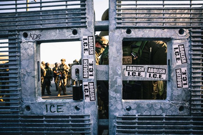 Agentes militarizados del Servicio de Inmigración y Control de Aduanas de los Estados Unidos (ICE), cierran una puerta y entran con fuerza para sofocar a los manifestantes mientras el papel de la instalación de Broadview, en Chicago, Estados Unidos