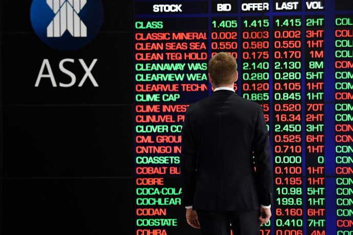 Archivo - A man is seen looking at the digital market boards at the Australian Stock Exchange (ASX) in Sydney, Monday, March 9, 2020.