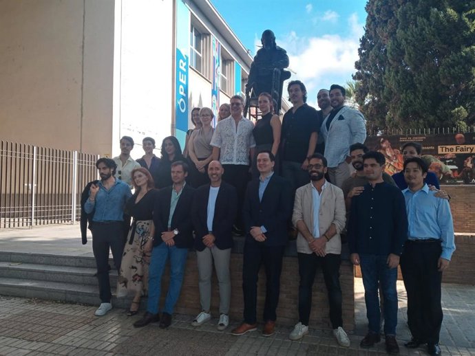 Foto de familia del elenco artístico de 'Don Giovanni' junto a la estatua dedicada a Mozart, el compositor austriaco de esta ópera, ubicada en el Paseo de Colón, en la fachada principal del Maestranza.