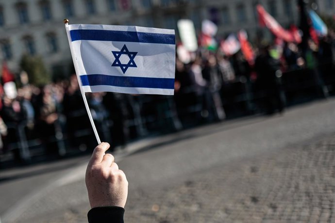 27 de setembro de 2025, Berlim, Alemanha: Um manifestante segura uma bandeira israelense durante a manifestação. Cerca de 60.000 a 100.000 pessoas marcharam em Berlim sob os slogans "Todos os olhos em Gaza" e "Parem o genocídio", exigindo um cessar-fogo, 