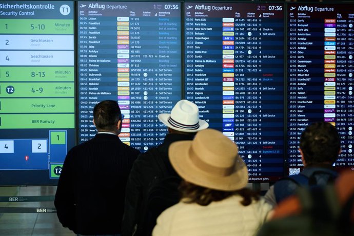28 September 2025, Brandenburg, Schoenefeld: People stand at BER Airport and look at the departure board. The airport service provider Collins Aerospace was the victim of a cyber attack on Friday last week. Several airports in Europe were affected, includ