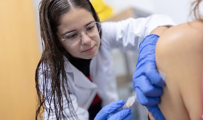 Una profesional sanitaria administra una vacuna a una paciente.