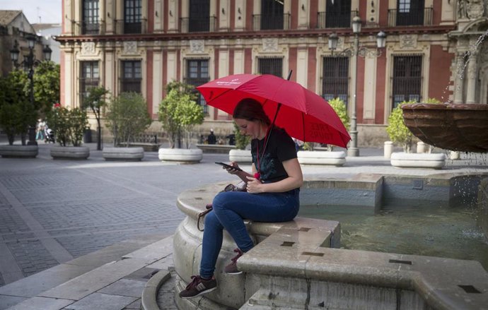 Archivo - Una guía turistica espera la llegada de clientes en Sevilla. Imagen de archivo.