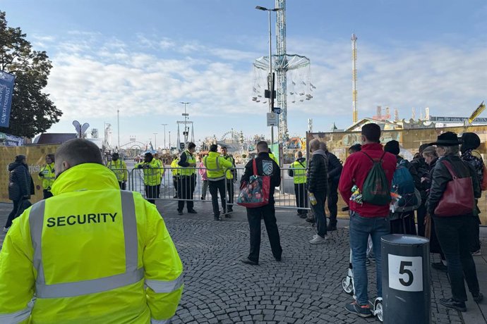 01 October 2025, Bavaria, Munich: People stand at a barrier at an entrance to the Oktoberfest in Munich, which remains closed until at least 5 p.m. due to an explosive threat linked to an earlier explosion in northern Munich and a letter from the perpetra