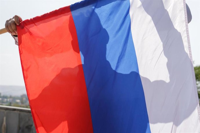 Archivo - Un hombre sostiene una bandera rusa que lo oculta