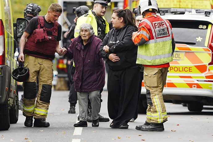 02 de outubro de 2025, Reino Unido, Manchester: Um membro do público é retirado do local de um incidente na sinagoga da Congregação Hebraica de Heaton Park em Crumpsall, Manchester, onde a polícia atirou em um suspeito depois que várias pessoas foram esfa
