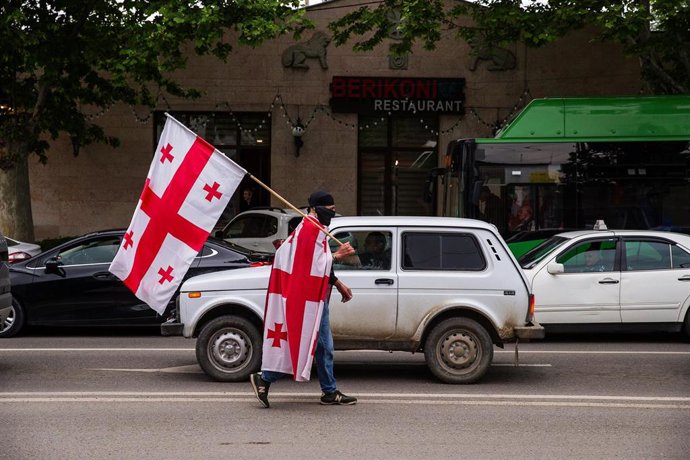 Archivo - Imagen de archivo de un manifestante con varias banderas de Georgia.