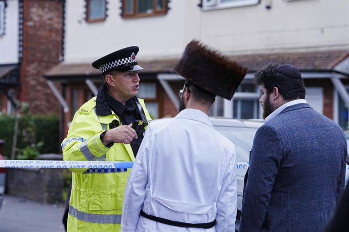 Un agente de Policía dialoga con dos hombres judíos frente a la sinagoga de la Comunidad Judía de Heaton Park en Manchester, Reino Unido, tras el atentado que ha matado a dos personas