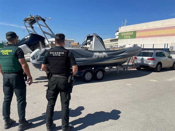 Agentes de la Guardia Civil junto a la embarcación recuperada
