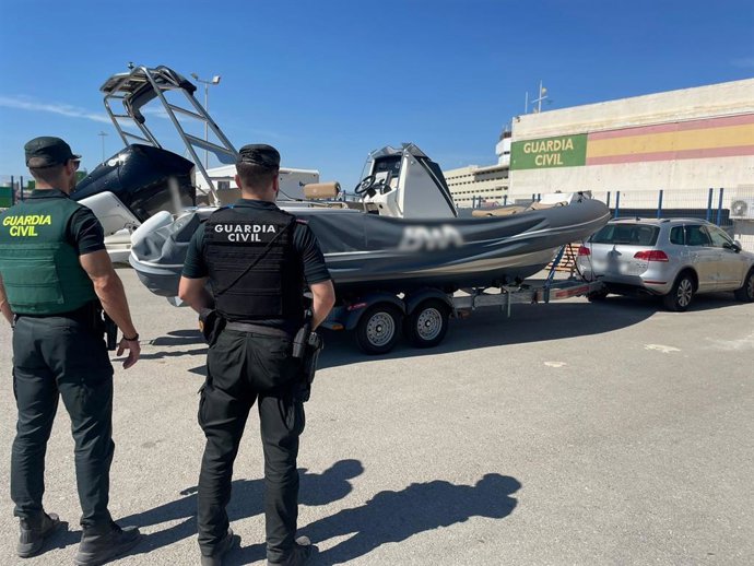 Agents de la Guàrdia Civil junt amb l'embarcació recuperada