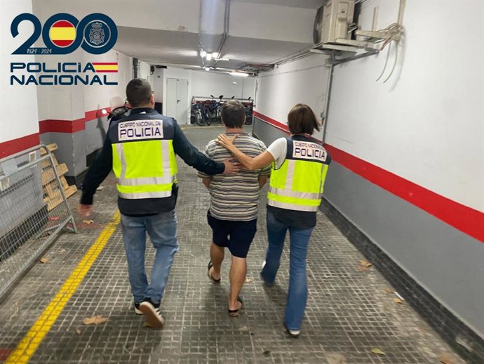 El detenido, de espaldas, escoltado por dos policías nacionales.