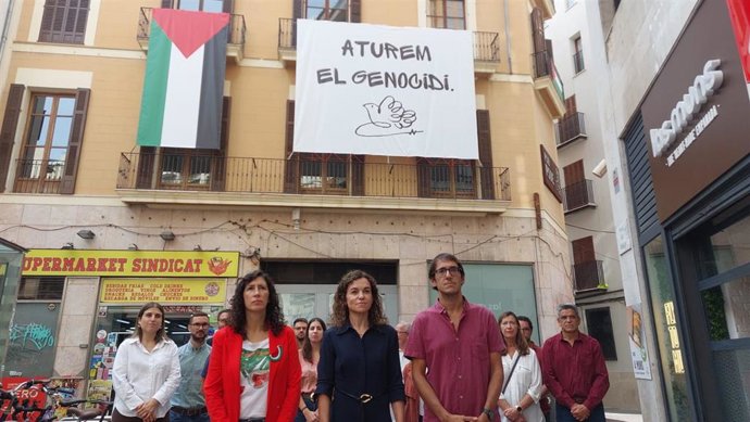 De izquierda a derecha, la secretaria general del PSIB de Mallorca, Amanda Fernández, la vicesecretaria general del PSIB, Rosario Sánchez, y el secretario general del PSIB de Palma, Iago Negueruela, frente a la sede del PSIB con una bandera Palestina.