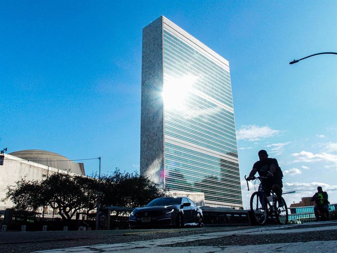 Archivo - September 9, 2024, New York, New York, USA: Full building shot of the United Nations HQ  from 1st avenue with sun reflection in late afternoon and silhouette of biker on 1st avenue.