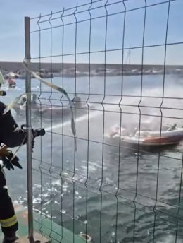 Imagem de bombeiros apagando um incêndio em um barco.