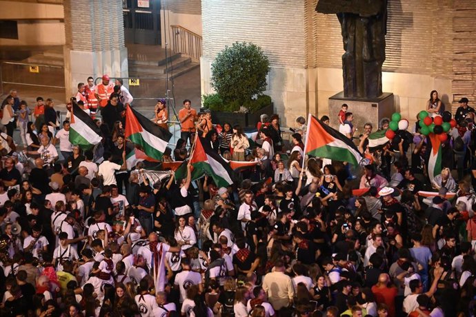 Un grupo de personas con banderas palestinas durante el pregón de inicio de las Fiestas del Pilar, desde el balcón del Ayuntamiento de Zaragoza.