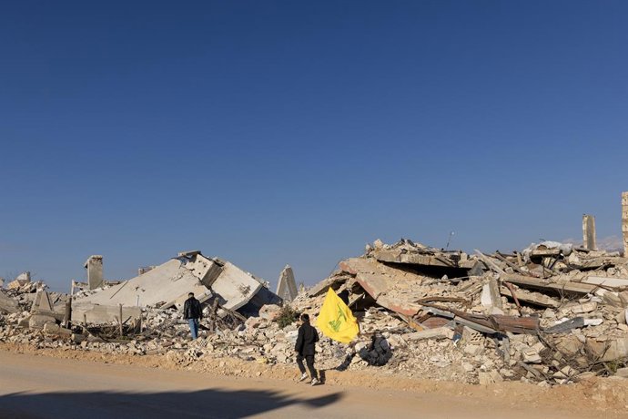 Archivo - Arquivo - 28 de fevereiro de 2025, Kfarkela, Líbano: Um menino corre com uma bandeira do Hezbollah ao lado de casas destruídas pelo exército israelense em 28 de fevereiro de 2025 em Kfarkela, Líbano. Mais tarde, soldados israelenses atiraram dua