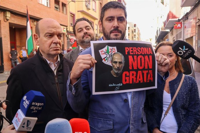 El portavoz de Vox en las Cortes, Alejandro Nolasco, sostiene un cartel con el que insta a declarar persona non grata al portavoz y fundador de la Casa Palestina de Aragón, Ibrahim Abayat, en una comparecencia frente a la sede de Casa Palestina.