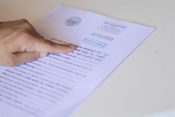 Archivo - Una mujer señala una escritura de compraventa de una hipoteca.