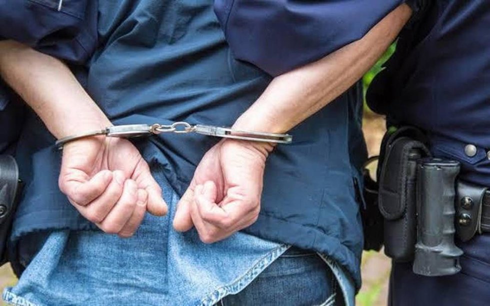 Imagen de recurso de una personas detenida y esposada junto a un agente de la autoridad.