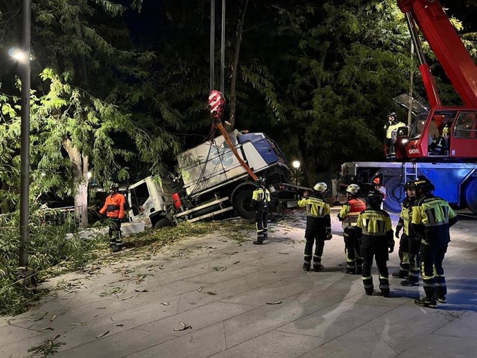 Bomberos de Madrid rescatan una baldeadora de limpieza que había perdido el control quedando encajada entre dos árboles y cerca de caer por una pendiente en la Cuesta de la Vega, en el centro de la ciudad.