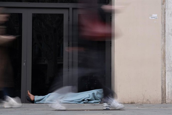 Archivo - Varias personas pasan delante de una persona sin hogar, en el barrio del Raval de Barcelona.