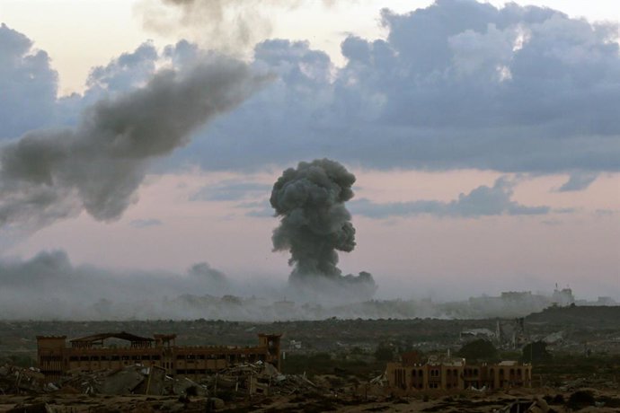 7 de outubro de 2025, Cidade de Gaza, Faixa de Gaza, Território Palestino: A fumaça se eleva sobre o sul da Cidade de Gaza após uma série de ataques aéreos israelenses, enquanto o sol nasce sobre tendas que abrigam palestinos deslocados na área de Nuseira