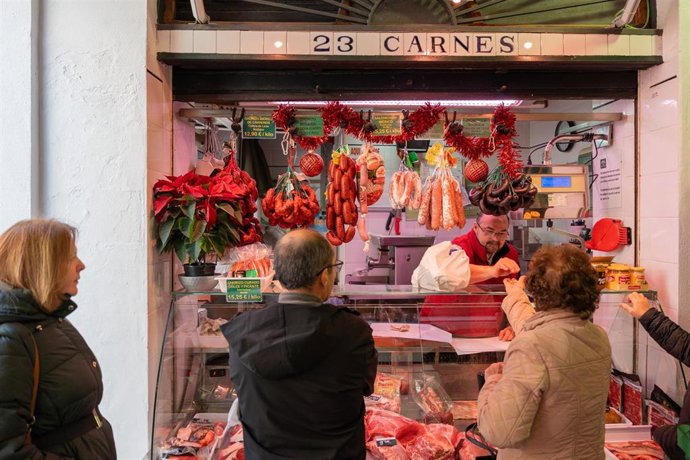 Archivo - Varias personas comprando en un mercado de Sevilla
