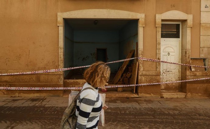 Archivo - Una mujer camina junto a una zona cubierta de barro, a 28 de noviembre de 2024, en Paiporta, Valencia (Comunidad Valenciana). ARCHIVO. 
