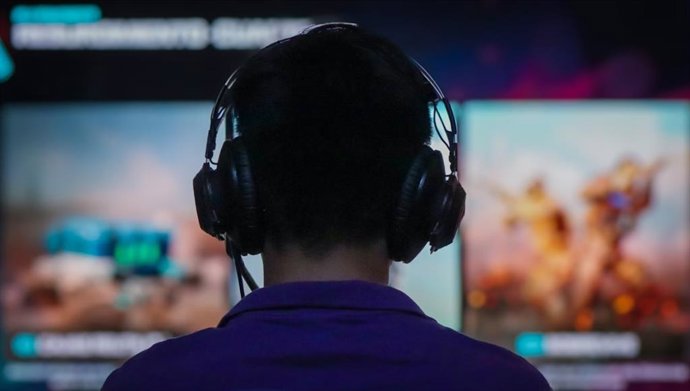 Menino com fones de ouvido jogando na frente da tela