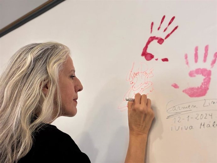 María Pagés firmando debajo de la huella de su mano, que ha estampado en la tercera planta del Teatro Cervantes