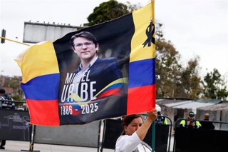 Archivo - Una persona ondea una bandera colombiana con una foto de Miguel Uribe Turbay durante su funeral