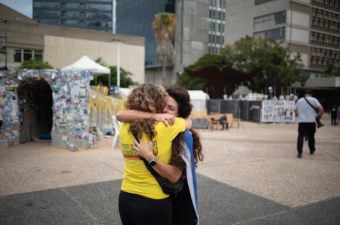 09 de outubro de 2025, Israel, Tel Aviv: Dois israelenses se abraçam, enquanto as pessoas se reúnem na praça dos reféns em Tel Aviv para comemorar o acordo de cessar-fogo. Após dois anos de guerra, Israel e o Hamas concordaram com a primeira fase do plano