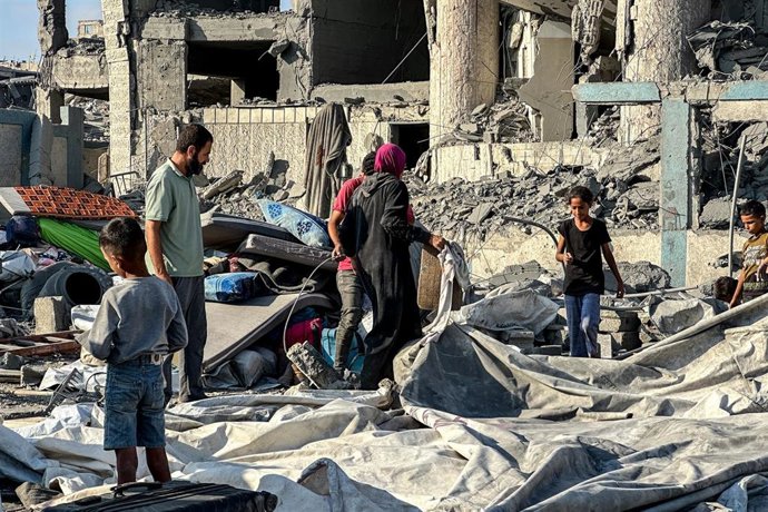 Archivo - Civiles palestinos entre los escombros de un edificio atacado en la Franja de Gaza