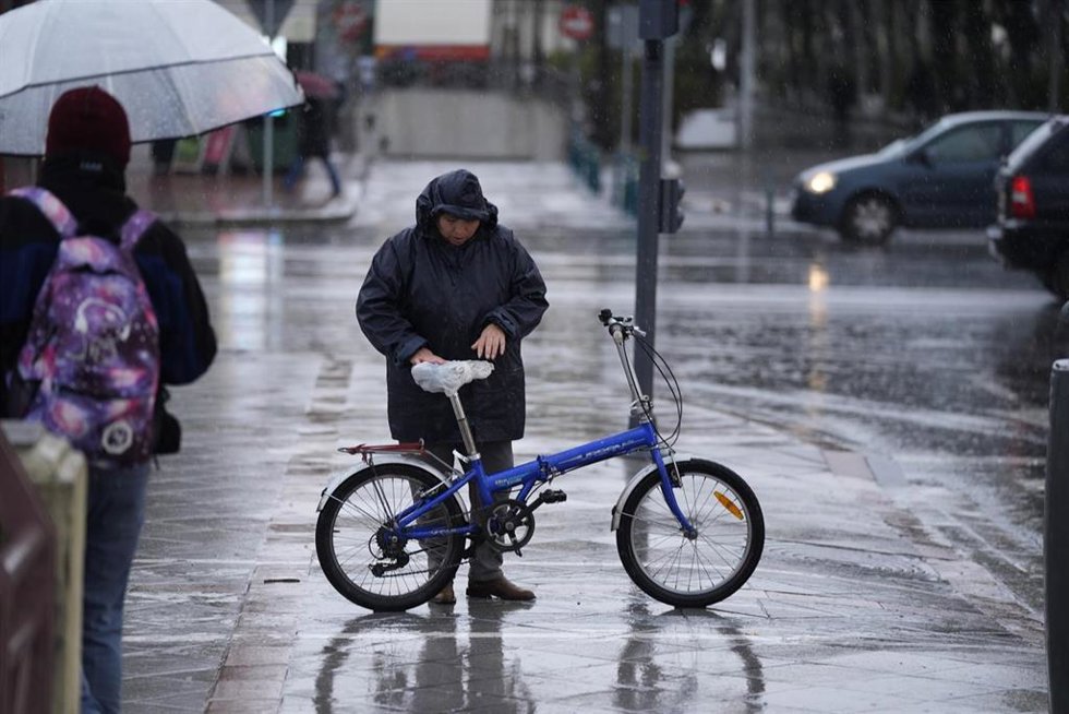 Archivo - Una persona se protege de la lluvia con un impermeable. 