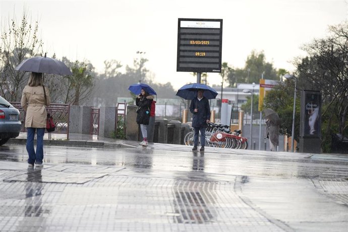 Archivo - Varias se protegen de la lluvia con un paraguas. A 03 de marzo de 2025, en Sevilla (Andalucía, España). Un total de seis provincias estarán bajo aviso por fenómenos meteorológicos este lunes en Andalucía. Lo más destacado es el riesgo de nivel n