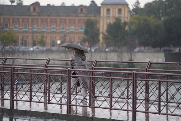 Archivo - Una persona se protege de la lluvia con un paraguas. A 03 de marzo de 2025, en Sevilla (Andalucía, España). Un total de seis provincias estarán bajo aviso por fenómenos meteorológicos este lunes en Andalucía. Lo más destacado es el riesgo de niv