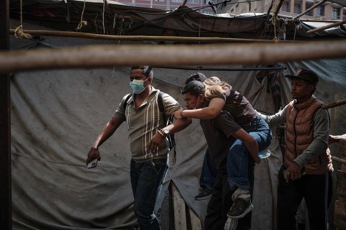25 September 2025, Madagascar, Antananarivo: A man carries a woma on his back after being injured during a protest organized by the Gen Z movement to denounce water and power shortages and government mismanagement. Photo: Iako Randrianarivelo/ZUMA Press W