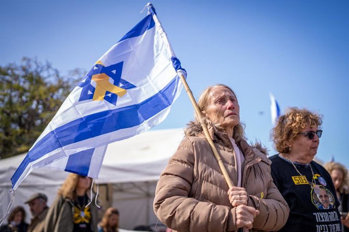 Archivo - 20 de fevereiro de 2025, Israel, Tel Aviv: Uma pessoa chora segurando uma bandeira israelense na Praça dos Reféns, em Tel Aviv, antes da esperada libertação dos restos mortais de quatro reféns israelenses pelo Hamas. De acordo com o Hamas, os mo
