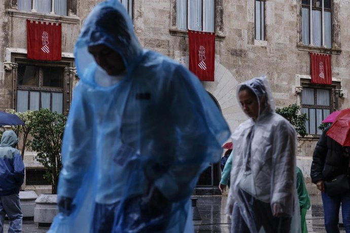 Varias personas con chubasqueros pasean, a 9 de octubre de 2025, en Valencia, Comunidad Valenciana (España). La Agencia Estatal de Meteorología (AEMET) ha activado la alerta naranja por precipitaciones en Valencia lo que ha obligado al Ayuntamiento a susp