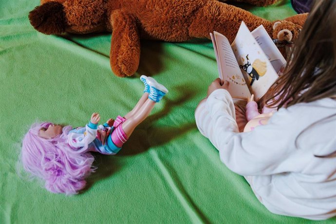 Archivo - Una niña juega con sus regalos de Navidad.