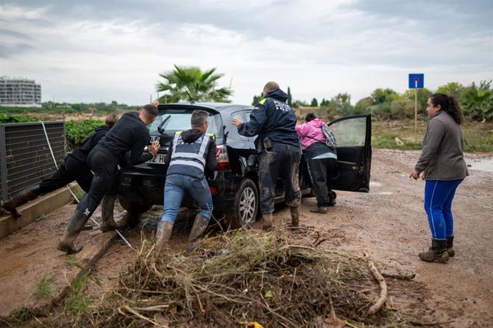 Vecinos de La Ràpita (Tarragona) tratan de sacar del barro un coche atrapado tras el episodio de fuertes lluvias
