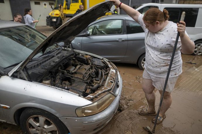 Una mujer observa el motor de un coche lleno de barro en La Ràpita (Tarragona)
