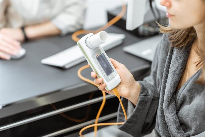 Archivo - Paciente sosteniendo un espirómetro, instrumento médico para medir los movimientos respiratorios, primer plano