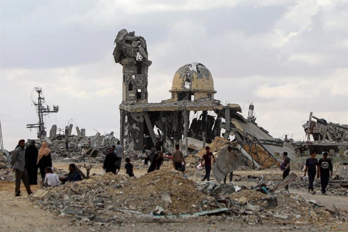 GAZA, 13 de outubro de 2025 -- Palestinos caminham pelos escombros de edifícios destruídos após retornarem a Khan Younis, no sul da Faixa de Gaza, em 12 de outubro de 2025. O acordo de cessar-fogo entre Israel e o Hamas entrou em vigor na sexta-feira.